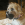 Ein brauner Hund sitzt auf einem Bett und hat ein KONG Extreme Spielzeug im Maul.
