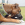 En brun hund, der sidder i en gård med en sort KONG-bold i munden.