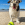 Perro blanco, marrón y negro con pelota de tenis KONG en la playa.