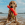 Um cão castanho na praia pingando água e segurando um brinquedo de água KONG laranja na boca.
