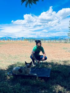 Jess Thomas avec son chien à l'extérieur qui est couché sur un tapis pour chien