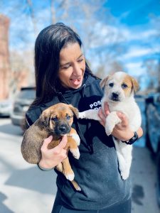 Jess Thomas holding two puppies outside
